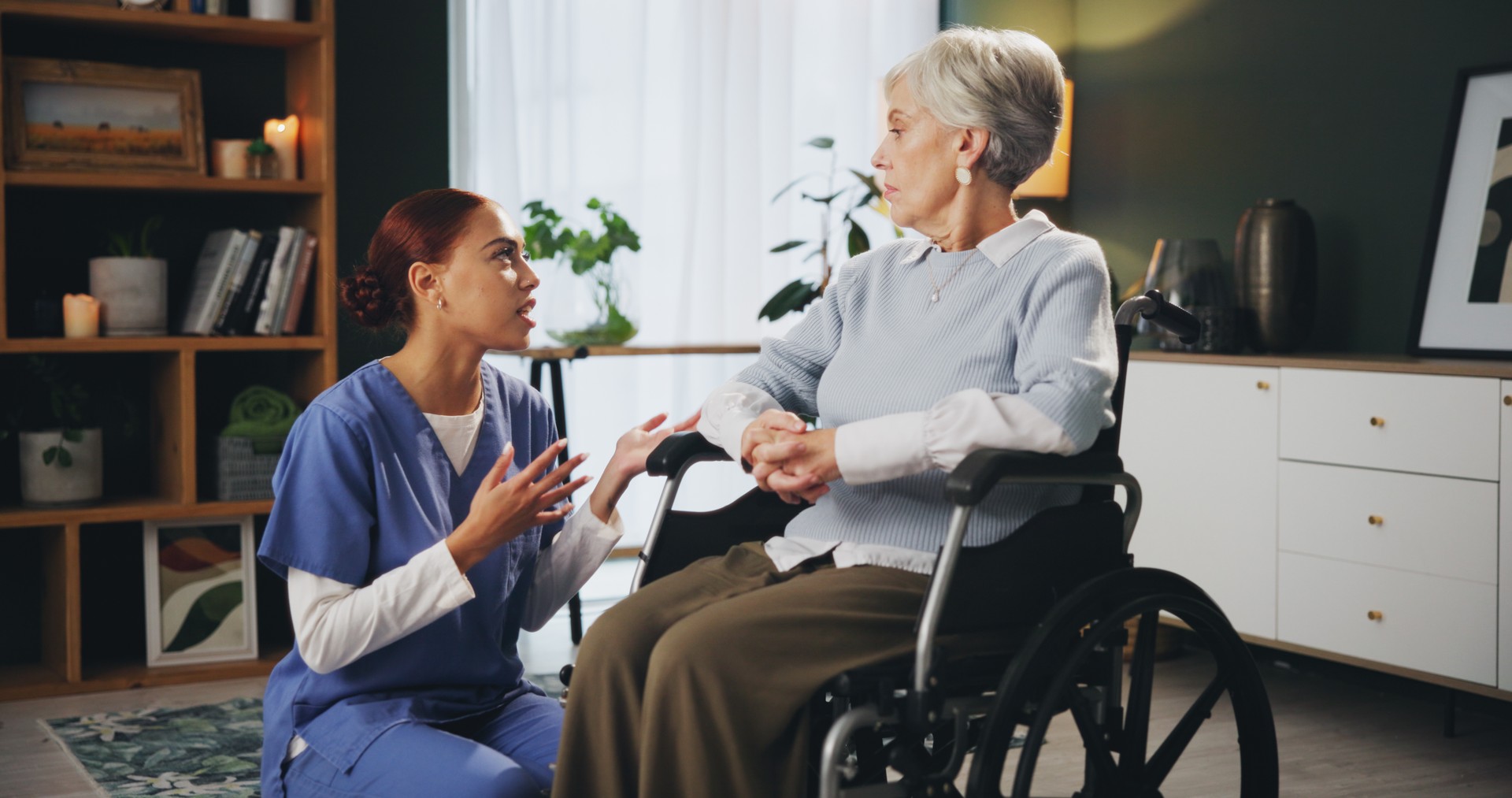 Nurse, senior woman and wheelchair at retirement home for healthcare, support and checkup. Caregiver, person with a disability and conversation for medical service,  physiotherapy and care or help