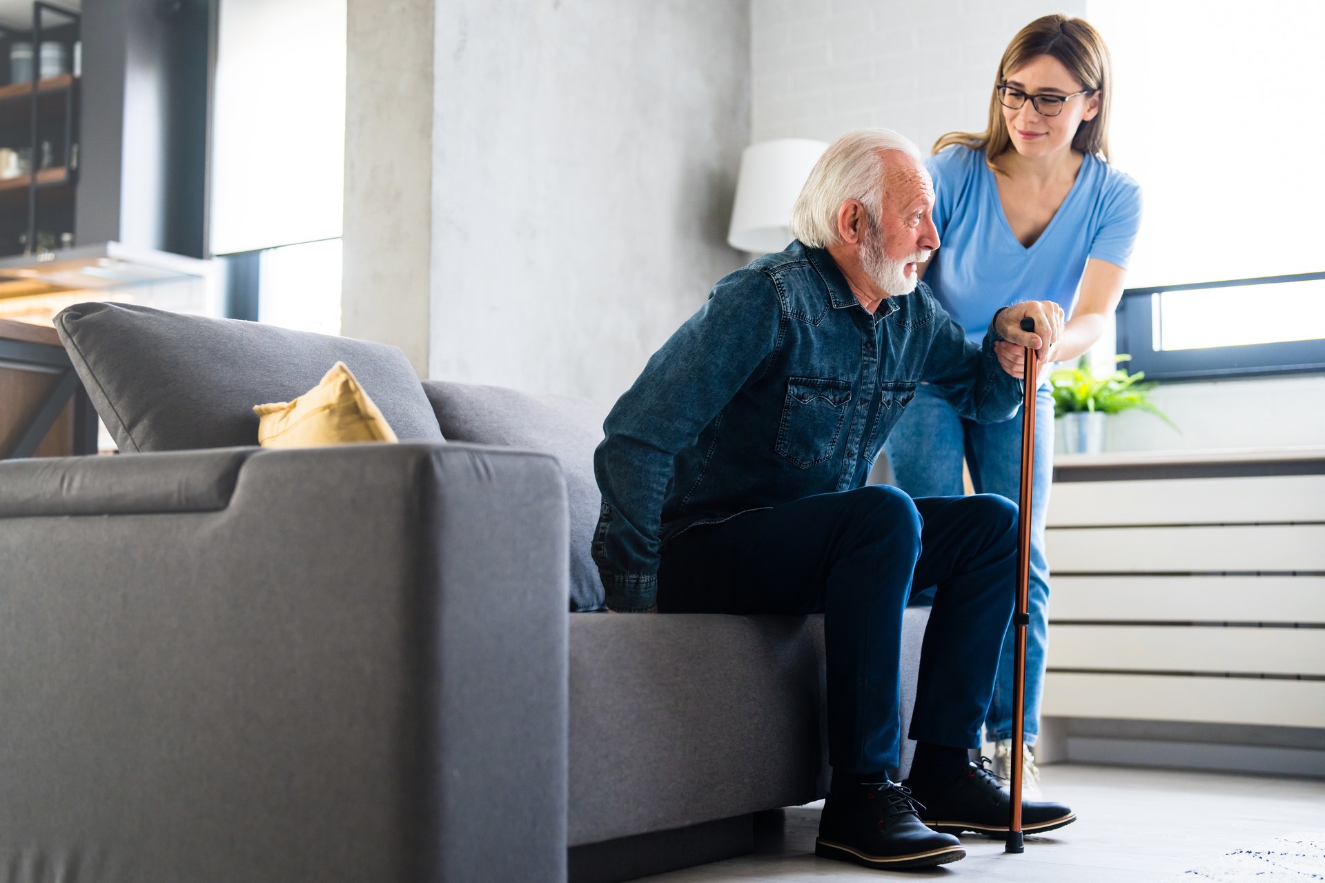 Caring nurse supporting patient while getting up from bed and move